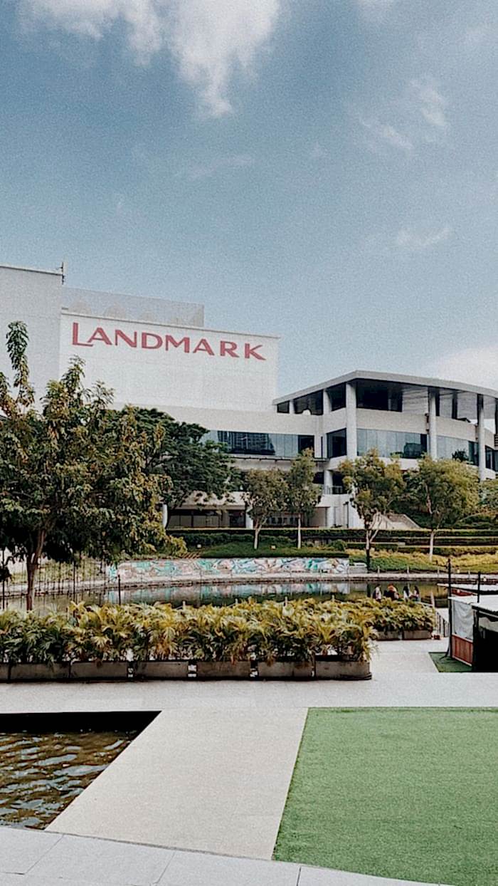 Contemporary shopping mall with lush landscaping and clear sky.
